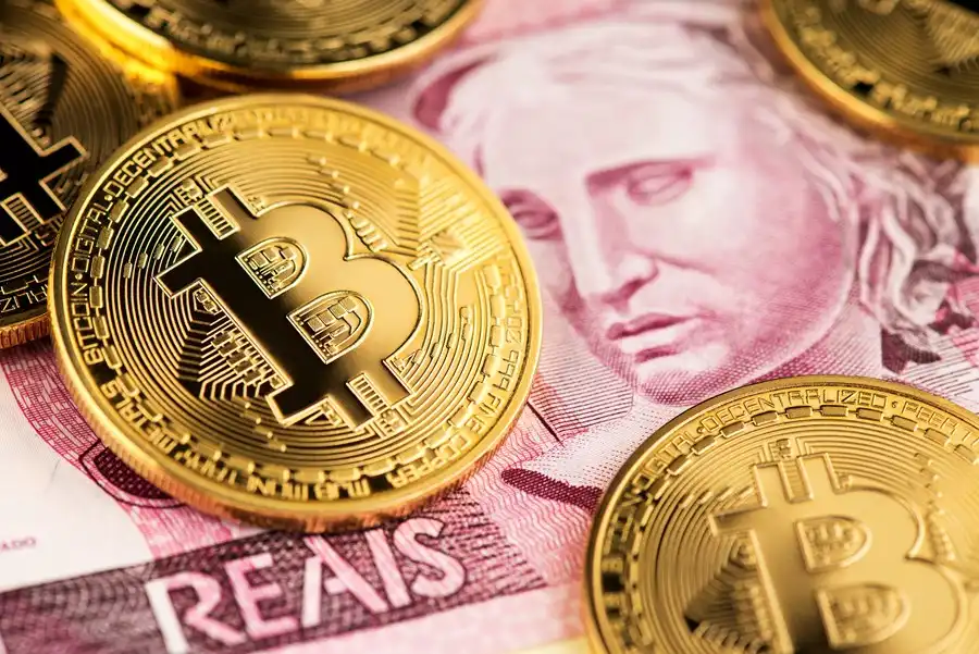 Moedas de Bitcoin sobre cédula de real, simbolizando a comparação entre criptomoedas e o DREX.